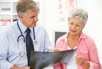 Doctor showing an elderly woman how vertebroplasty works using an X-ray image.